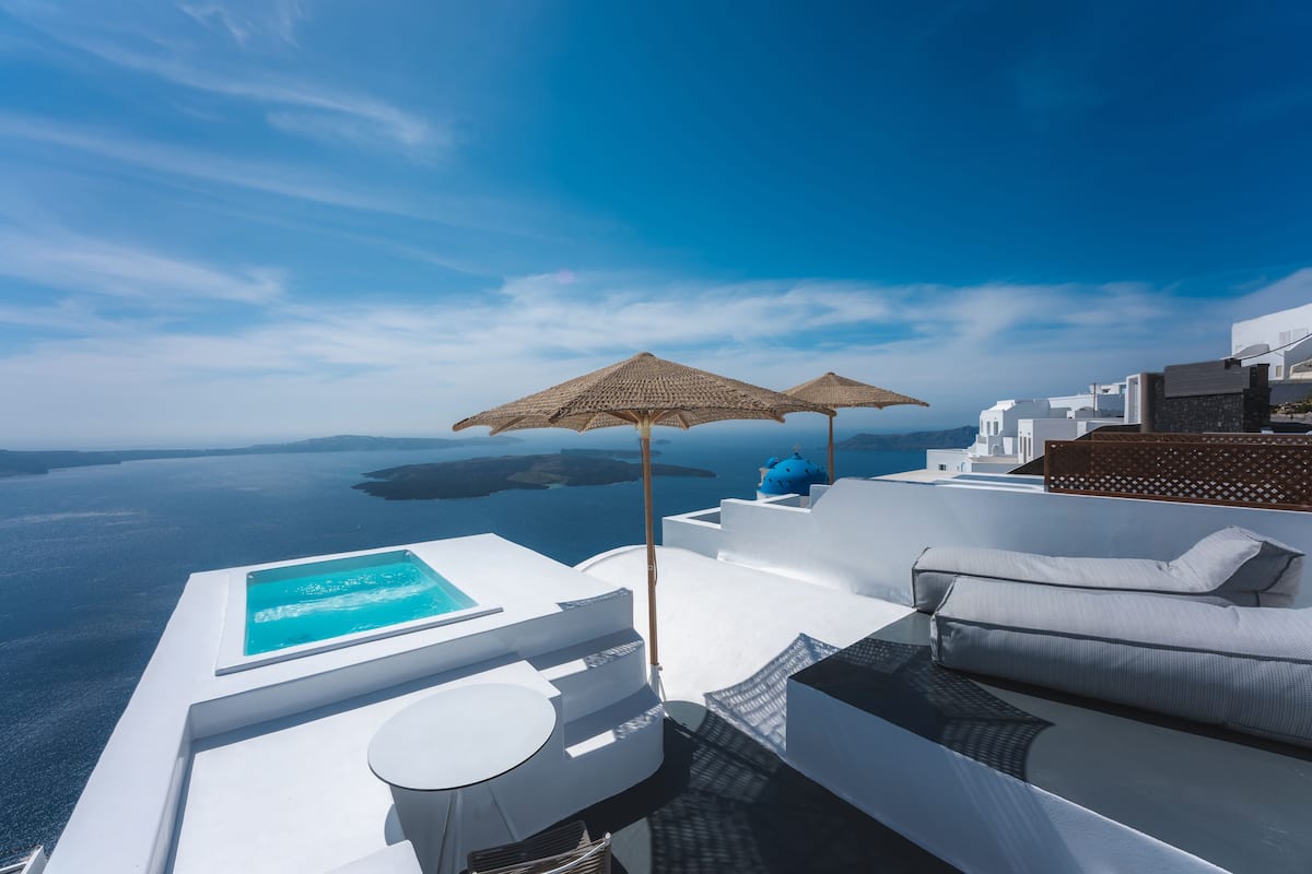 Une terrasse sur le toit avec une piscine à débordement, un espace détente et une vue sur la mer.