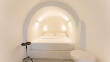 A minimalist bedroom with a bed under an arched ceiling, a small round table, and a toilet.