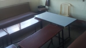 A classroom with wooden desks and benches, a television on a wall, and a window providing natural light. - Kikuyu Guest House (Kikuyu)