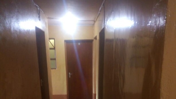 A narrow, dimly lit hallway with a wooden door at the end. - Kikuyu Guest House (Kikuyu)