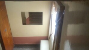 A narrow stairway with a bench at the bottom, a door on the left, and a wall-mounted air conditioning unit. - Kikuyu Guest House (Kikuyu)