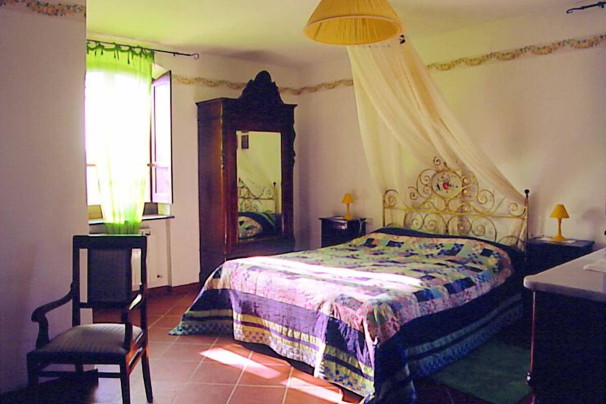 Une chambre à coucher avec un lit, une chaise, un bureau et un miroir.