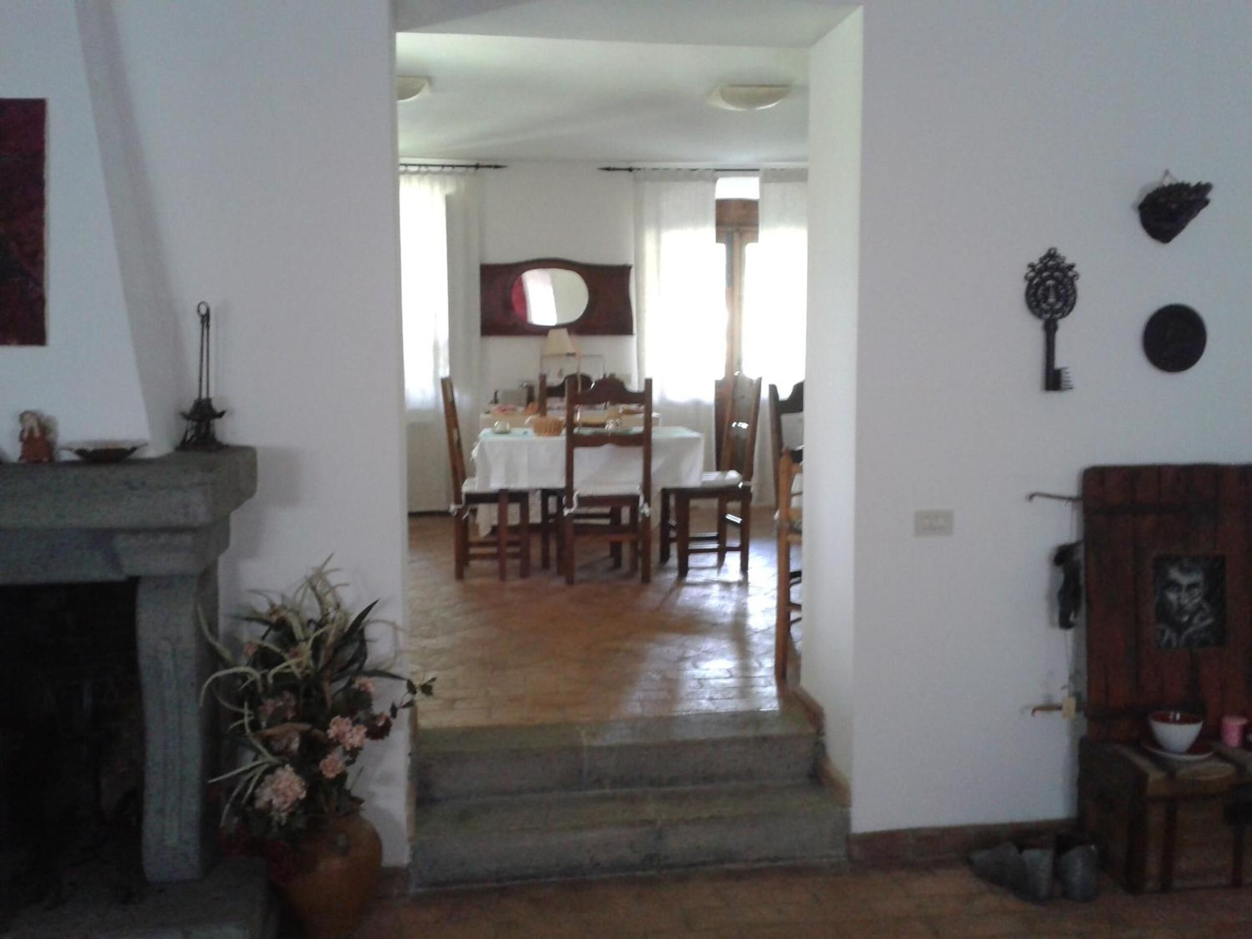 A dining area with a table set for four, a fireplace, and a staircase leading to another room.