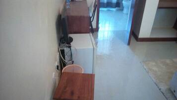 A small wooden table in a narrow hallway with a white wall and a door leading to a bathroom.
