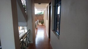 A corridor with tiled flooring, a metal railing on one side, and windows on the other.