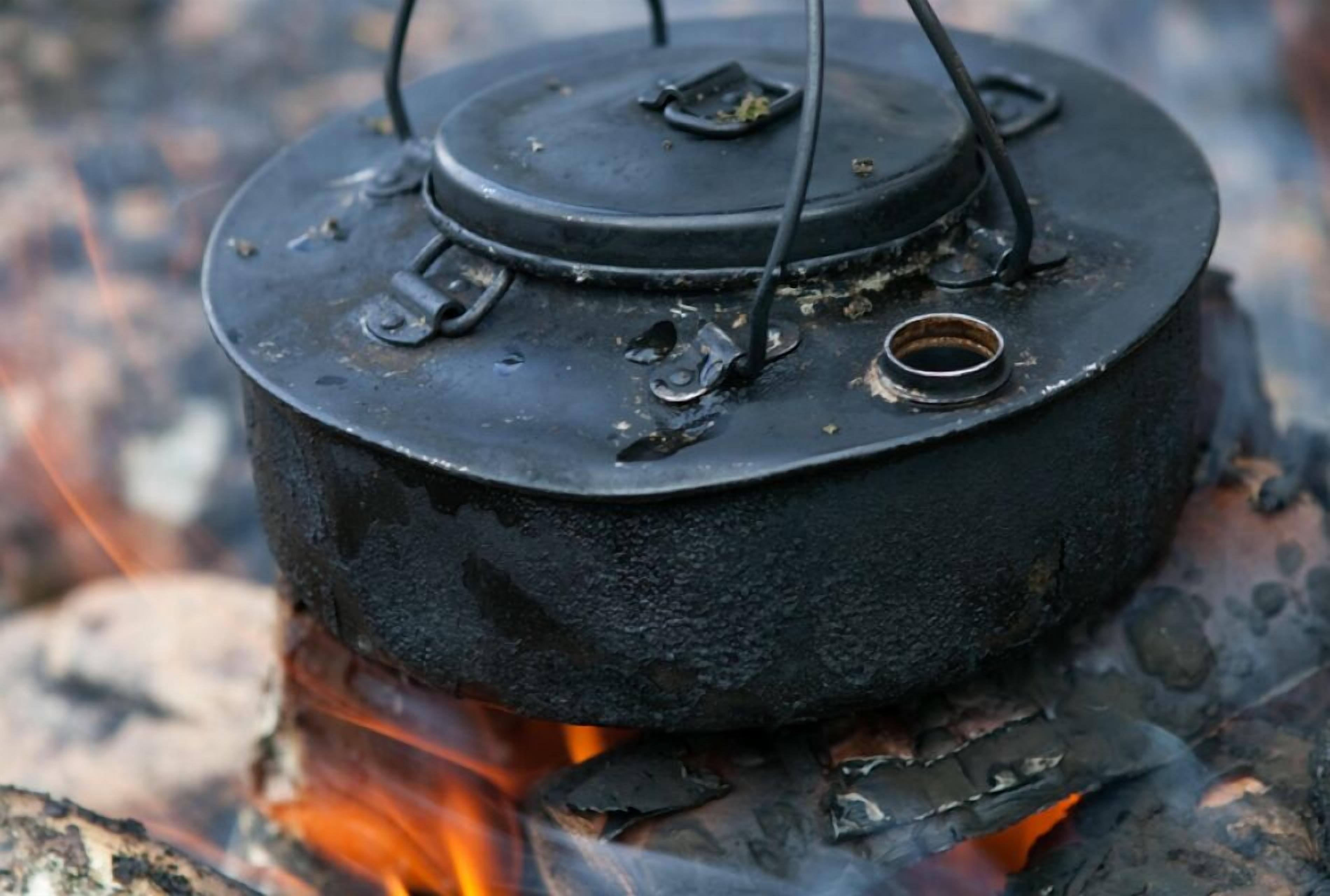 A black pot with a lid on a fire.