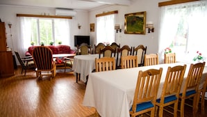 A dining area with wooden chairs and tables, a sofa, and a television.
