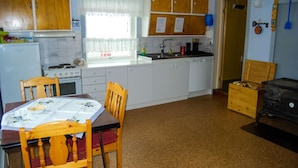 A compact kitchen with wooden cabinets, a stove, a sink, and a dining table with chairs.