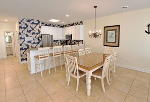 A modern kitchen with white cabinets, a dining table with chairs, and a chandelier.