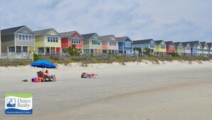 A row of beach houses with a sandy beach in the foreground.
