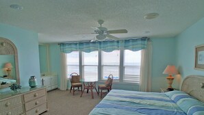 A bedroom with a bed, dresser, chairs, and a ceiling fan.