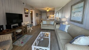 A living room with a TV, sofa, coffee table, and dining area. - Inlet Pointe 37 - Second Row (Channelfront) in Garden City Beach (Garden City)