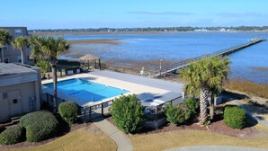 A swimming pool with a deck, surrounded by palm trees and a view of a body of water. - Inlet Pointe 37 - Second Row (Channelfront) in Garden City Beach (Garden City)