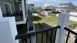 A residential area with multiple houses, a staircase leading to a balcony, and a swimming pool. - Just Beachin' - Second Row complex in Garden City Beach (Garden City)