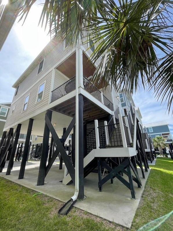 Stilted residence with a balcony and a well-manicured lawn.