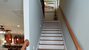 A wooden staircase with a handrail, leading to a landing with a ceiling fan and pendant lights. - Just Beachin' - Second Row complex in Garden City Beach (Garden City)