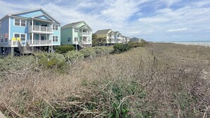 Una propiedad frente al mar con varias casas, algunas elevadas sobre pilotes, y un paseo marítimo de madera que lleva a la playa.