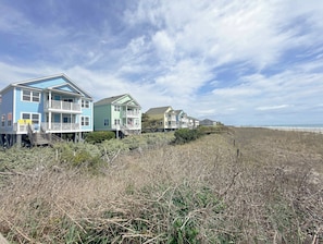 A beachfront property with multiple houses, some elevated on stilts, and a wooden boardwalk leading to the beach. - Portofino II 315B - Oceanfront in Surfside Beach (Surfside Beach)