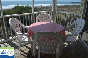 Relax in this outdoor seating area with a table and four chairs, overlooking the ocean and a picturesque pier.