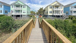 Una pasarela de madera que conduce a una hilera de coloridas casas de playa con balcones y barandillas.
