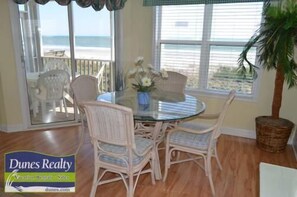 Enjoy meals in this dining area with a round table and wicker chairs, offering a view of the beach and ocean.