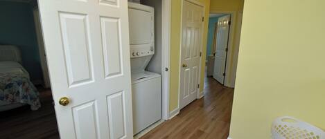 A hallway with wooden flooring, white doors, and a laundry area with a washing machine.
