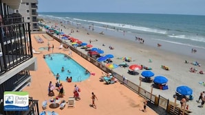 Un complexe hôtelier en bord de mer doté d’une piscine, de parasols et offrant une vue sur l’océan.
