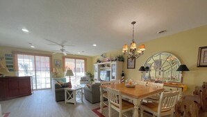 Un salon spacieux comprenant un coin repas, un ventilateur de plafond et un lustre.