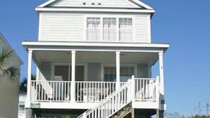 Un immeuble blanc à deux étages, doté d’un balcon et d’un escalier menant à l’étage supérieur.