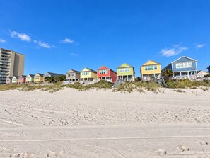 A row of beach houses with a sandy beach in the foreground. - Portofino IV 2002 - Oceanfront in Garden City Beach (Garden City)