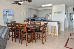 A modern kitchen with white cabinets, a stainless steel refrigerator, and a microwave.