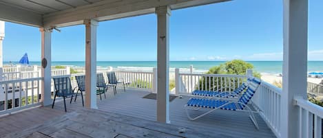 A wooden deck with chairs and a view of the beach.