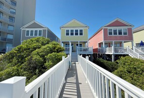 A pathway leading to a row of colorful houses with balconies, surrounded by greenery.
