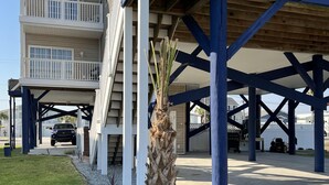 Ein Anwesen am Strand mit einer überdachten Terrasse, einer Palme und einem Fahrzeug auf der Einfahrt.