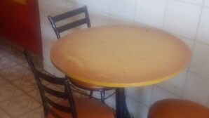 Una mesa redonda con dos sillas, cada una con asiento acolchado, ubicada sobre un suelo de baldosas con diseño geométrico.