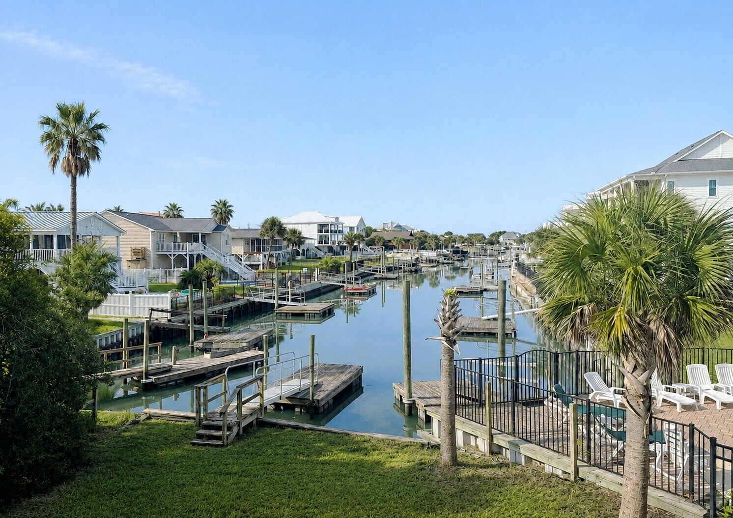 A marina with docked boats, a grassy area with lounge chairs, and residential buildings in the background.