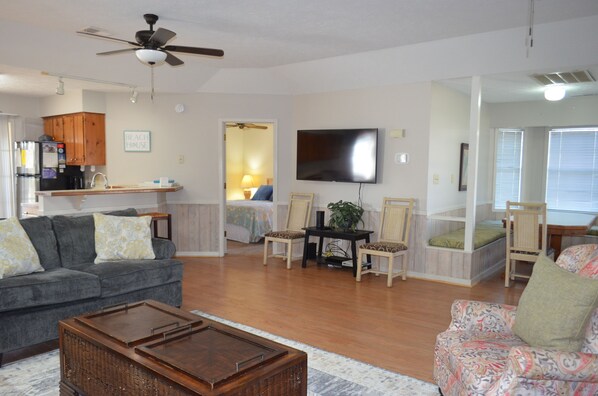 A spacious living room with a sofa, chairs, a coffee table, and a TV. - Up the Creek - Walk to Beach (Channelfront) in Garden City Beach (Garden City)