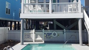 Una casa de dos pisos con balcón, piscina y valla de piquete blanca.