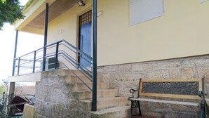 Ein Gebäude mit einer Steintreppe, die zu einem Balkon führt, einer Bank und einer Tür mit einem Fenster darüber.
