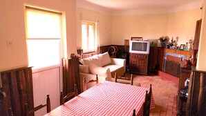 Ein gemütliches Zimmer mit Esstisch, einer Couch, einem Fernseher und einem Schrank.