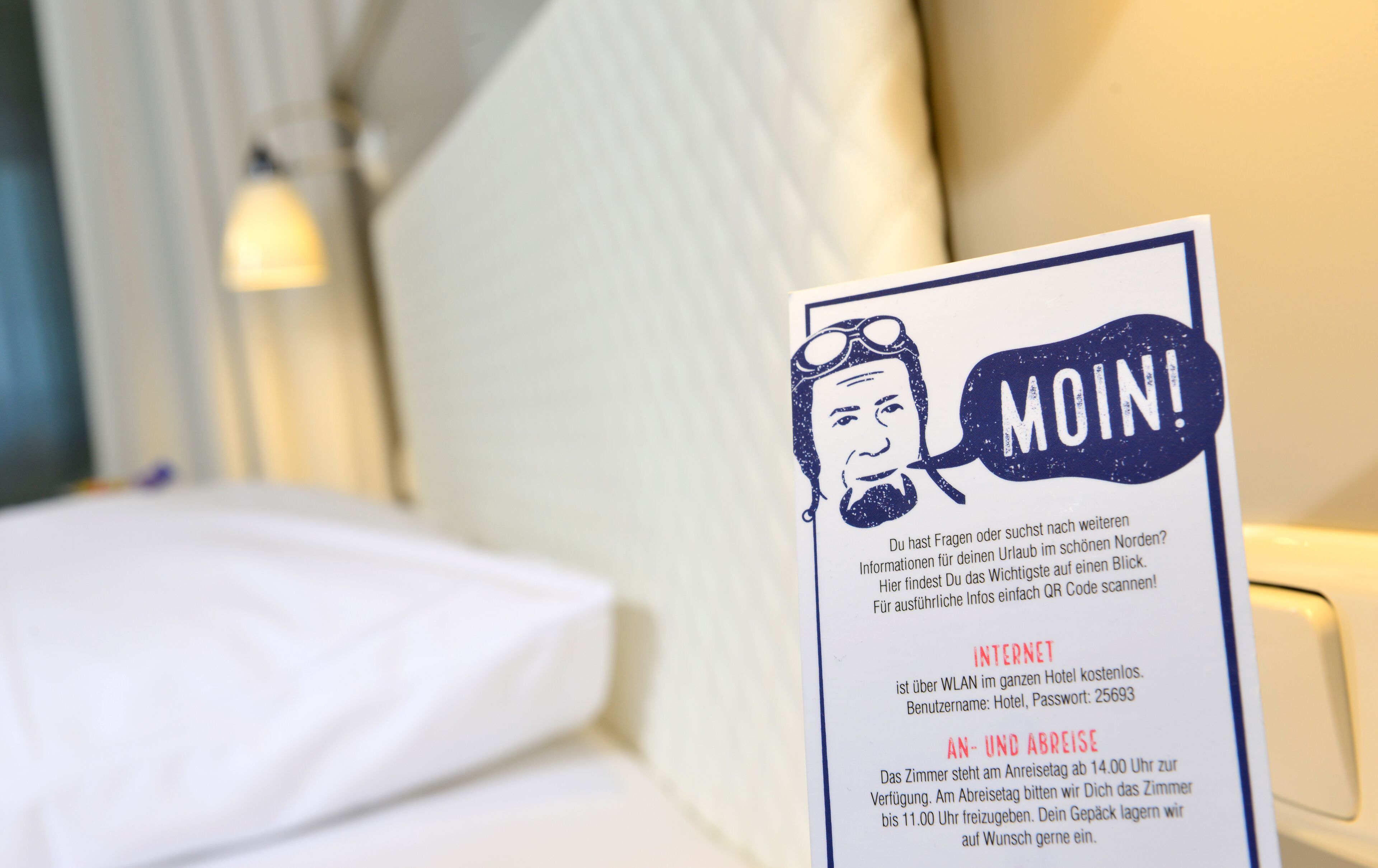 Camera d'albergo con un letto, un comodino e un cartello con informazioni su Wi-Fi e disponibilità delle camere.