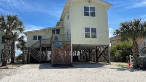 Un bâtiment à deux étages doté d’un espace extérieur couvert, d’un escalier et d’une enseigne indiquant qu’il offre une vue sur la plage.