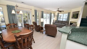 A spacious living area with a dining table, chairs, a sofa, and a television. - Pebble Beach - Second Row in Surfside Beach (Surfside Beach)
