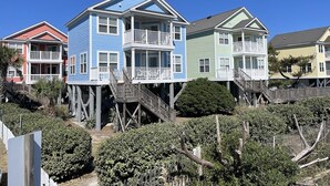 Une rangée de maisons colorées, dotées de terrasses et de balustrades en bois, entourées de verdure.