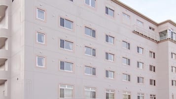 A multi-story hotel with a flat facade, a central entrance, and a visible parking area.