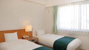 A hotel room with two beds, a bedside table with a lamp, and a window with sheer curtains. - Hotel Laurel (Shinhidaka)