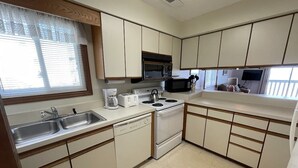 A compact kitchen with white cabinets, a microwave, a stove, and a dishwasher. - Surfside Landing 101 - Oceanfront in Surfside Beach (Surfside Beach)