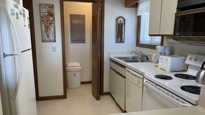 A compact kitchen with a refrigerator, microwave, stove, and dishwasher. - Surfside Landing 101 - Oceanfront in Surfside Beach (Surfside Beach)