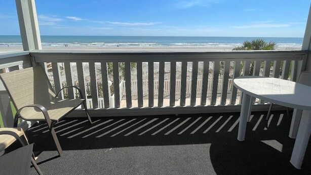 A balcony with a view of the beach, a table, and two chairs. - Surfside Landing 101 - Oceanfront in Surfside Beach (Surfside Beach)
