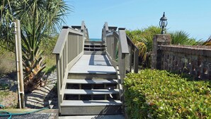 A wooden boardwalk leading to a beach with a lamp post and a palm tree. - Surfwatch II 202 - Oceanfront in Surfside Beach (Surfside Beach)